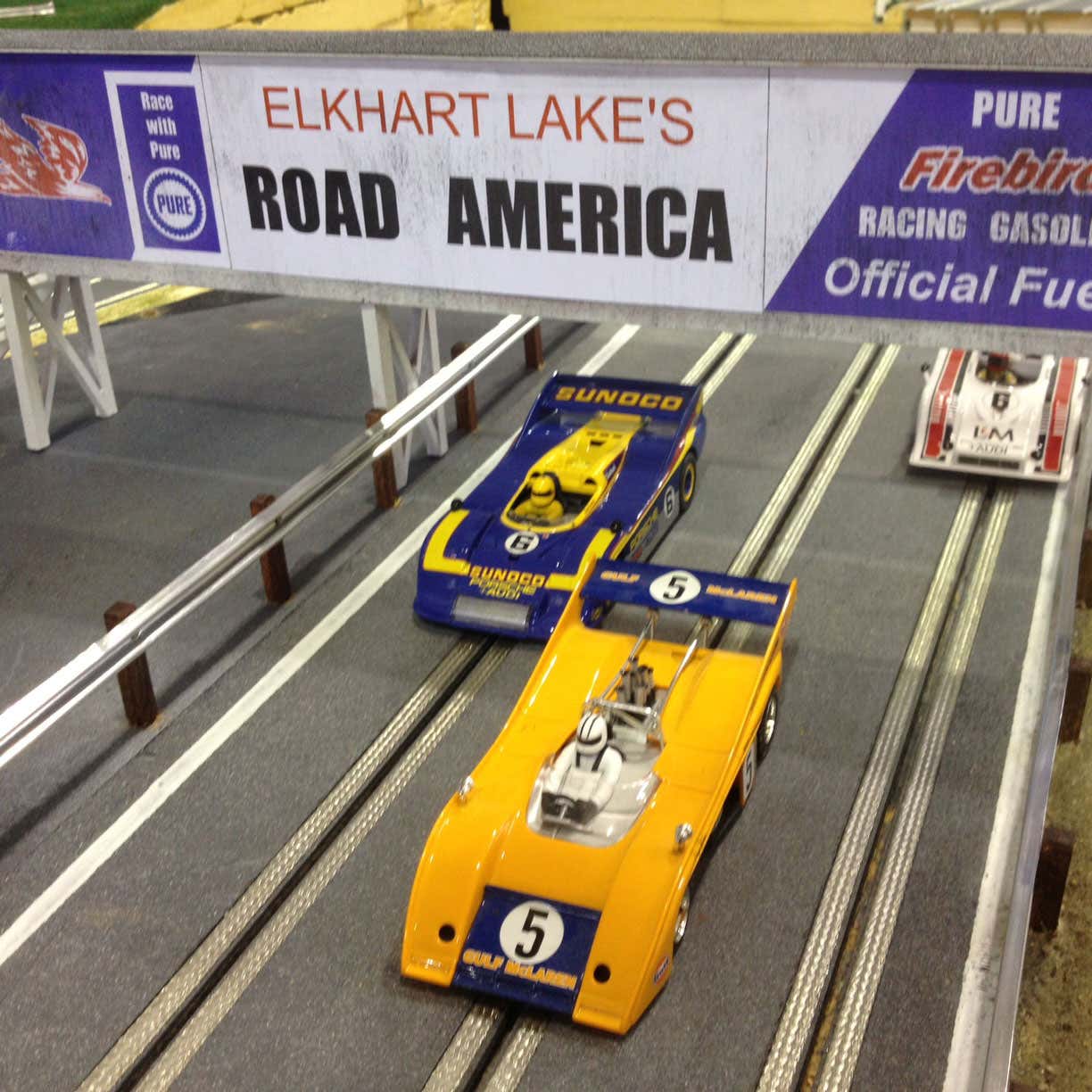 Un gros plan de voitures courant sur une piste réalisée par Slot Mods Raceways. 